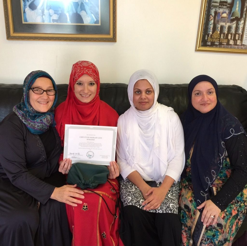 Chryston in red abaya with her Shahada certificate with ISDHH women